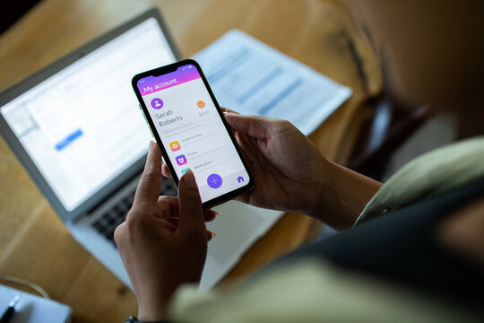 Adult using mobile banking app at home office, focused