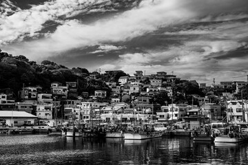 斜面に広がる港町の家並みと漁船のモノクロ風景