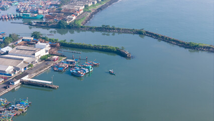 This aerial view shows a cilacap fishing harbor filled with boats and breakwaters.
