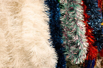 Colorful tinsel garland decorations hanging for sale in a store during the festive season for holiday celebrations and party decor