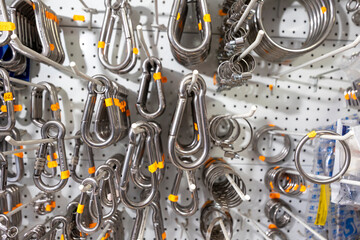 Metal carabiners, clips, and rings hanging on pegboard