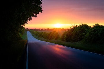 Scenic road through golden hills at sunset with distant mountain range