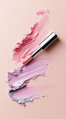 A silver lipstick tube is placed on a pastel pink background with swatches of pink and purple makeup.