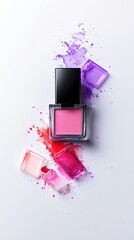 A pink blush compact is surrounded by vibrant splashes and swatches of pink, red, and purple makeup on a clean white surface.