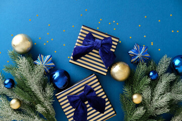 Top view of Christmas blue gifts and fir branches on dark background