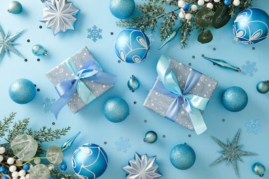 Christmas light blue background with gift boxes, blue baubles and silver stars