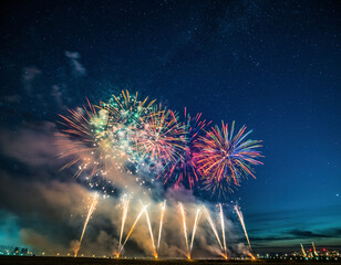 Brilliant fireworks burst across the night sky above a glowing city skyline