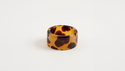 Tortoiseshell patterned resin ring presenting warm tones on plain white background