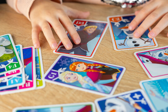child, little girl excitedly exploring Disney Frozen playing cards, magical world favorite movie, childhood hobby, Frankfurt - November, 18, 2024