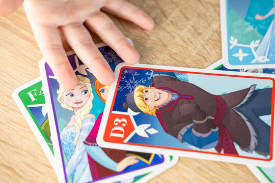 child, little girl excitedly exploring Disney Frozen playing cards, magical world favorite movie, childhood hobby, Frankfurt - November, 18, 2024