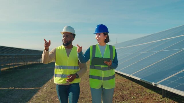 Workers discuss solar panel installation on a sunny day at a renewable energy site