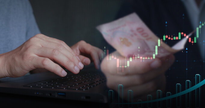 A detailed scene showing hands typing on a laptop with blurred banknotes and rising candlestick charts, symbolizing online trading, digital payments, financial growth, and real-time market analytics.
