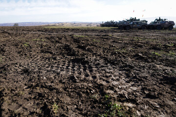 Details with armored vehicles tracks in the dirt during an exercise.