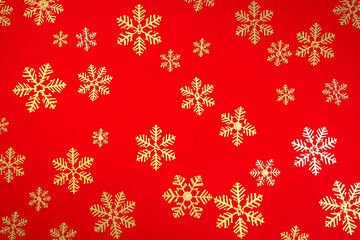 A bright and decorative holiday background featuring golden snowflake ornaments scattered across a vibrant red surface.