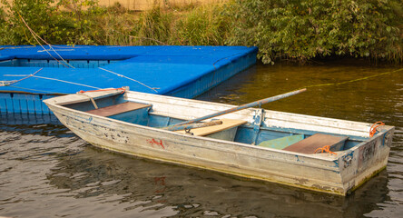 Aluminum rowboat by blue pontoon on water horizontal