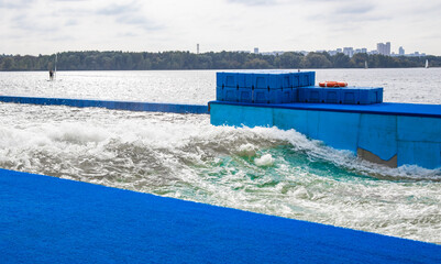 Artificial training wave for surfers on lake with blue platform