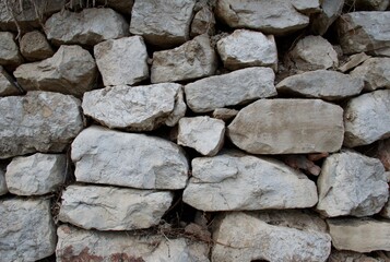 High-resolution close-up of a rugged stacked stone wall, showing natural rock textures, irregular shapes, and weathered surfaces—ideal for backgrounds, construction materials, or architectural design 