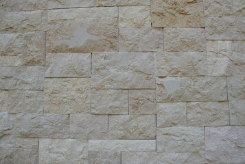 High-resolution beige stone wall texture featuring rough, natural rock surfaces and irregular block patterns. Ideal for backgrounds, architecture themes, construction materials, and design mockups.