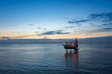 Aerial view of offshore jack up rig and offshore platform during sunset for oil and gas exploration and production.