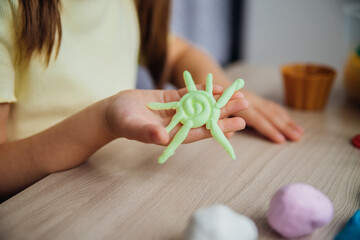 A little girl makes figurines out of colored airy plasticine, modeling dough. Hobbies for children's creativity, educational activities, development of fine motor skills of hands.