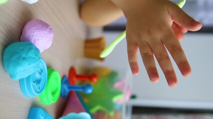 A little girl makes figurines out of colored airy plasticine, modeling dough. Hobbies for children's creativity, educational activities, development of fine motor skills of hands.