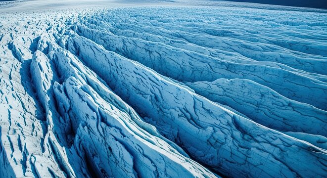 Majestic aerial view of a vast blue glacier with deep crevasses and textured ice formations, showcasing the raw power and beauty of a frozen polar landscape