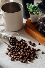 Coffee Beans Spilled on Table with Mug and Coffee Maker Background