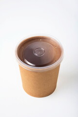 A single, cylindrical, brown kraft paper or waxed cardboard cup food container with a clear plastic lid. Studio shot, isolated on white, no people