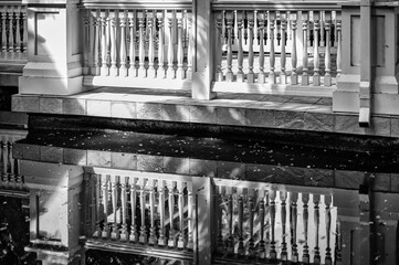Pavilion with White Decorative Wooden Railing Reflected in Calm Water.