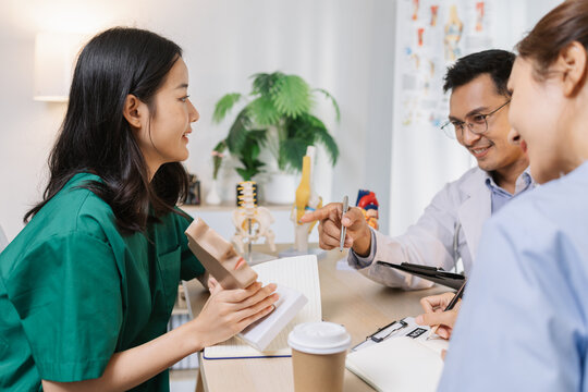 Doctor teaching medical team during a clinical session. Healthcare professionals learn together, discussing anatomy models and patient cases to enhance medical knowledge and treatment skills. - Powered by Adobe
