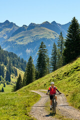 Naklejka premium woman riding her electric mountain bike in the Bregenz Forest Mountains near near village of Au, Vorarlberg, Austria 
