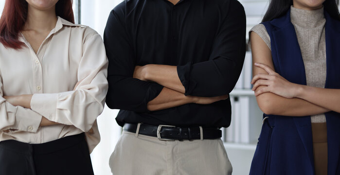 Startup business team posing with arms crossed in office: business plan and success.