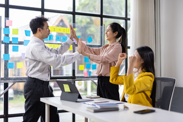 Diverse team celebrating a successful achievement with high-fives in office. Motivated colleagues express joy and teamwork.