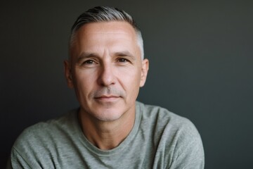 Obraz premium Mature man with neatly combed gray hair looking directly at the camera. He expresses confidence and a calm demeanor