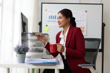 Asian businesswoman drinking coffee and working in office.