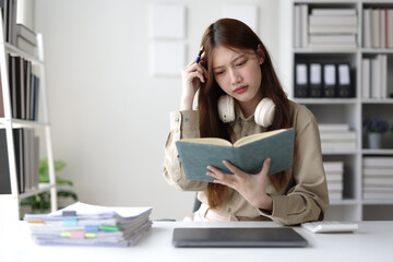 Stressed asian businesswoman having troubles understanding a document at office desk.