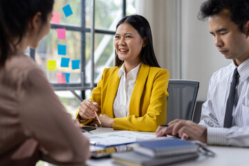 Business Team Engaging in Productive Meeting. Diverse group of professionals collaborating in a modern office setting. Smiling woman surrounded by colleagues taking notes and brainstorming.