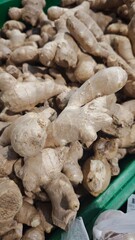 Fresh ginger roots with rough beige skin displayed in a crate at a farmers market. Concept of medicinal food, natural remedies and culinary spice