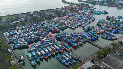 Crowded Cilacap harbor with many colorful fishing boats docked closely.