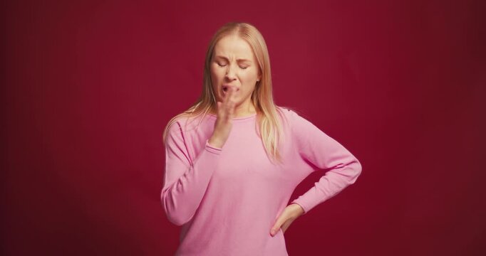 Serious pensive blonde woman to smell unpleasant odor o cover one's nose isolated on red background