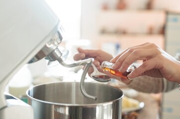 Hands carefully add flavor to a mixing bowl while preparing delicious Romanian mucenici. This traditional dish embodies cultural heritage and culinary skills