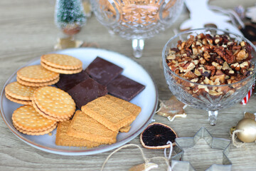 Various Christmas decorations, cookies, chocolate and nuts on wooden background. Selective focus.