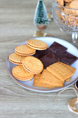 Various Christmas decorations, cookies, chocolate and nuts on wooden background. Selective focus.