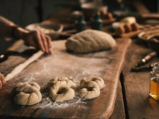 Hands skillfully shape dough into traditional Romanian Mucenici, surrounded by flour and kitchen tools. This activity captures the essence of Romanian culinary heritage