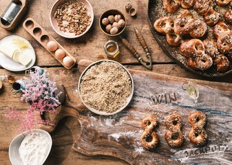 Delicious Romanian mucenici are being prepared on a wooden countertop, showcasing a variety of ingredients like nuts, flour, and eggs. The cozy atmosphere captures the essence of Romanian cuisine