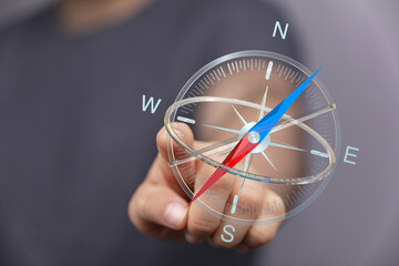 Close-up of a person's hand holding a compass, representing direction, navigation, and...