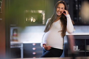 Pregnant woman smiling warmly while resting in a cozy kitchen setting