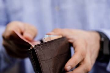 Close-up of a man's hands holding a wallet with money, ideal for financial concepts, budgeting, and saving, symbolizing wealth and prosperity.