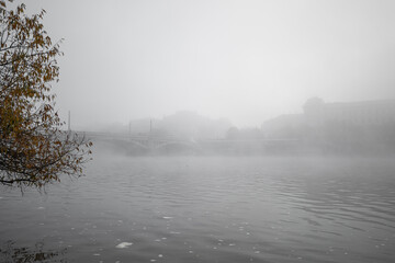 Fototapeta premium Vltava river flowing through thick fog covering Manes bridge and Rudolfinum, creating a mysterious atmosphere in prague