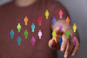 Hand pointing at colorful people symbols representing teamwork, diversity and unity. Digital connection for social networking and global collabo